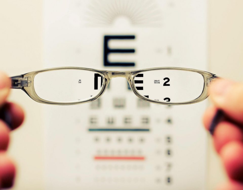 Person holding glasses in front of eyesight test